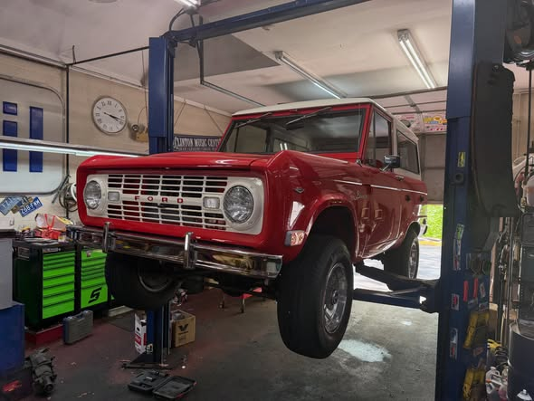 Red 1968 Ford Bronco on the lift during a power steering conversion